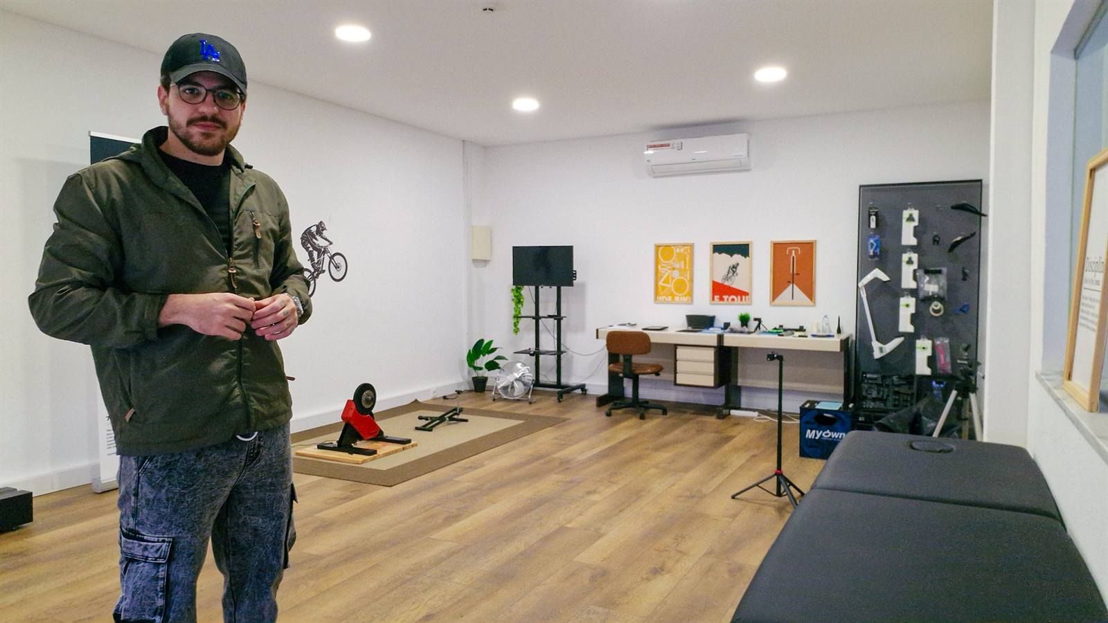Victor Castelo Branco no estúdio VTR Bike Lab, com a marquesa de avaliação, o rolo e o painel de ferramentas ao fundo